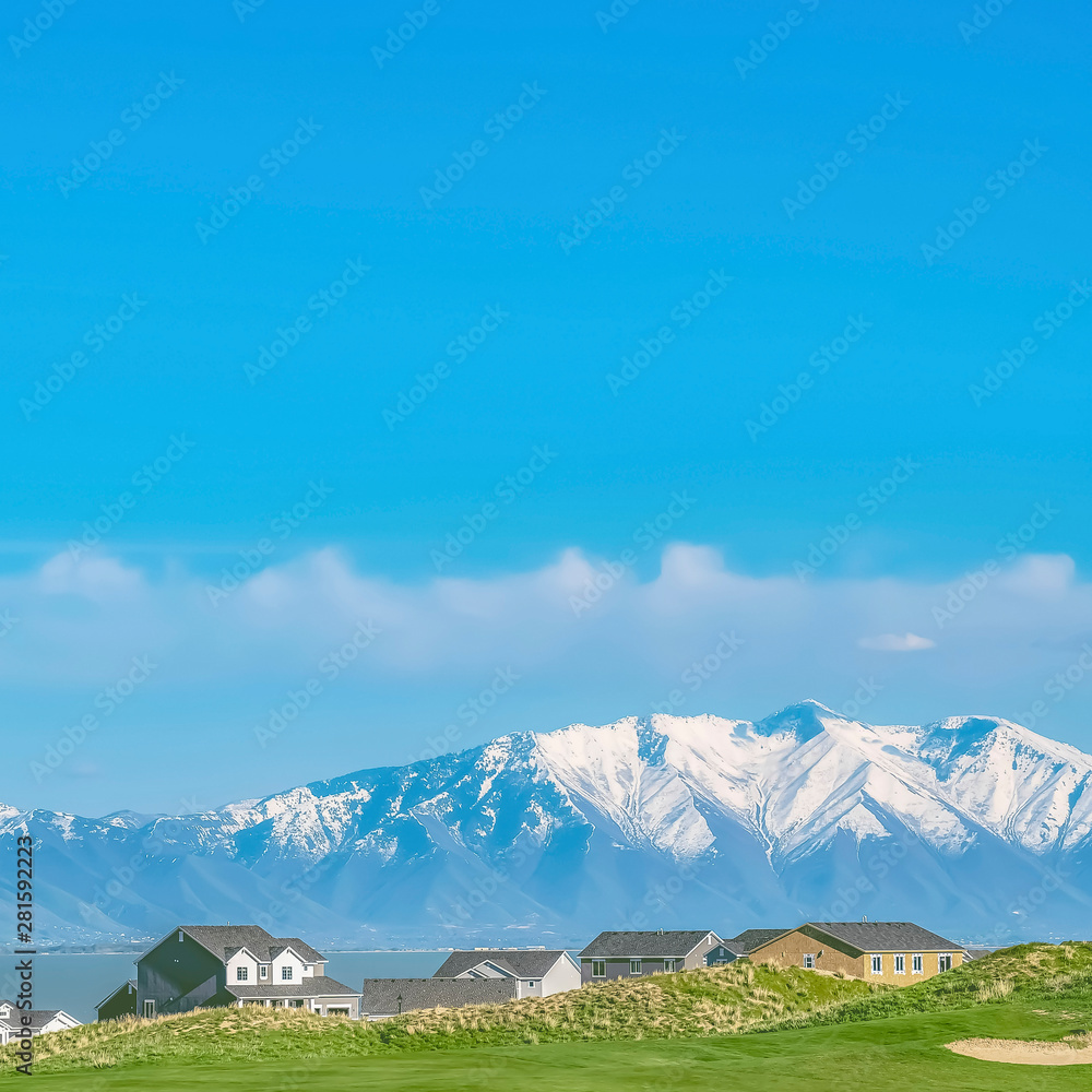 Fototapeta premium Residential area overlooking a lake and snow peaked mountain under blue sky