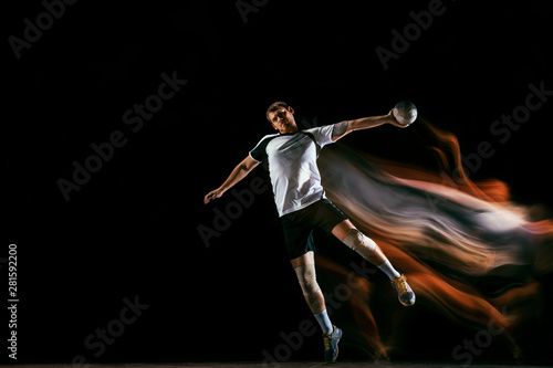 Caucasian young handball player in action and motion in mixed lights over black studio background. Fit male professional sportsman. Concept of sport  movement  energy  dynamic  healthy lifestyle.