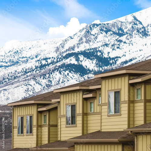 Exterior of houses with snow covered mountain and bright blue sky background