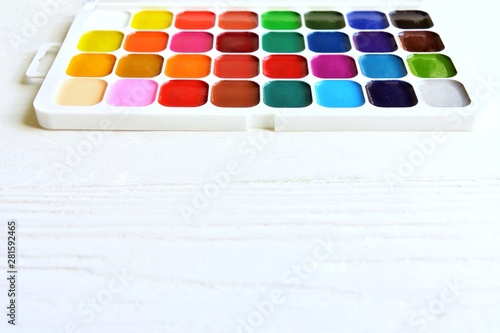 Bright multicolored aquarelle paints in paint box with selective focus on neutral background. Vivid watercolor paint. Palette with new bright watercolors for drawing. Back to school. Set for artist. C