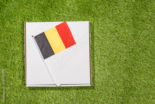 Paper box of pizza with Belgian  Flag on the grass. Concept. Top view