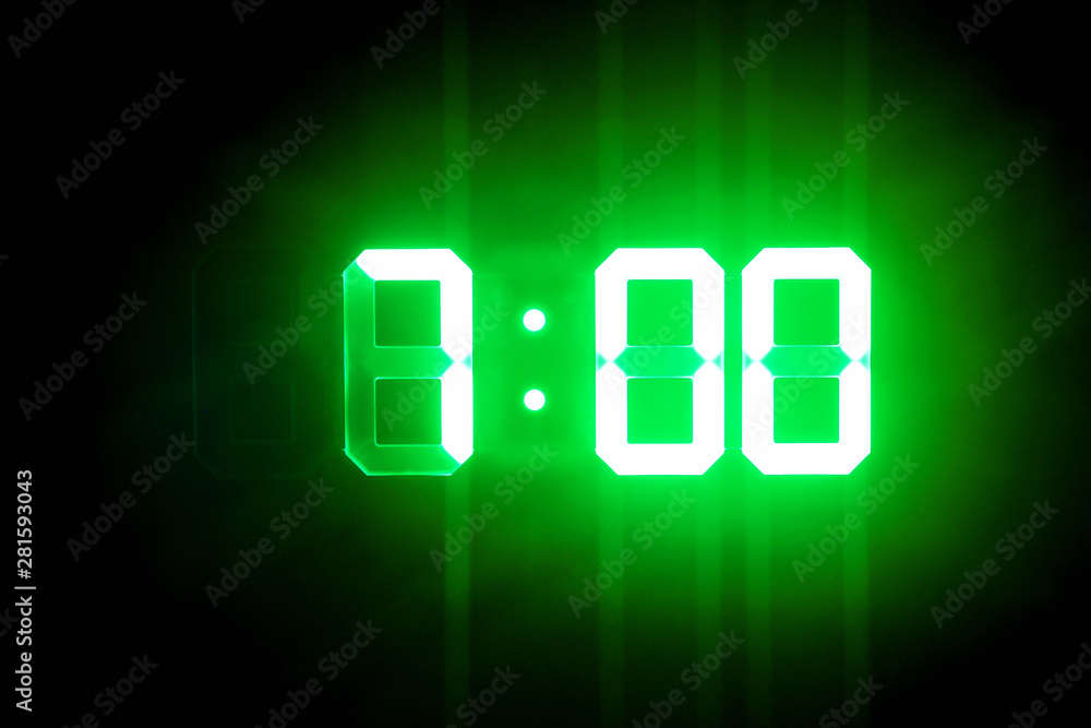 Green glowing digital clocks in the dark show 7:00 time Green glowing digital clocks in the dark show 7:00 time