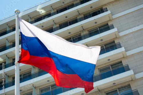The flag of the Russian Federation develops against the background of a multi-storey apartment complex