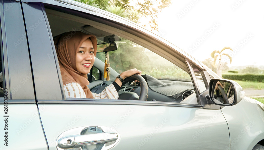 portrait of hijab women looking at the camera with a smile while sitting inside a car portrait of hijab women looking at the camera with a smile while sitting inside a car