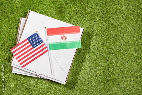 Paper box of pizza with flags of Iran and America on the grass. Concept of peace, partnership and friendship, . Top view