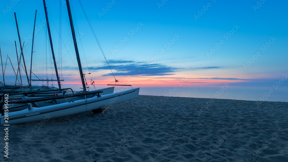 Fototapeta premium Sunrise with sailboats on the beach, Rosenfelder Strand on the Baltic Sea, Schleswig-Holstein. Northern Germany