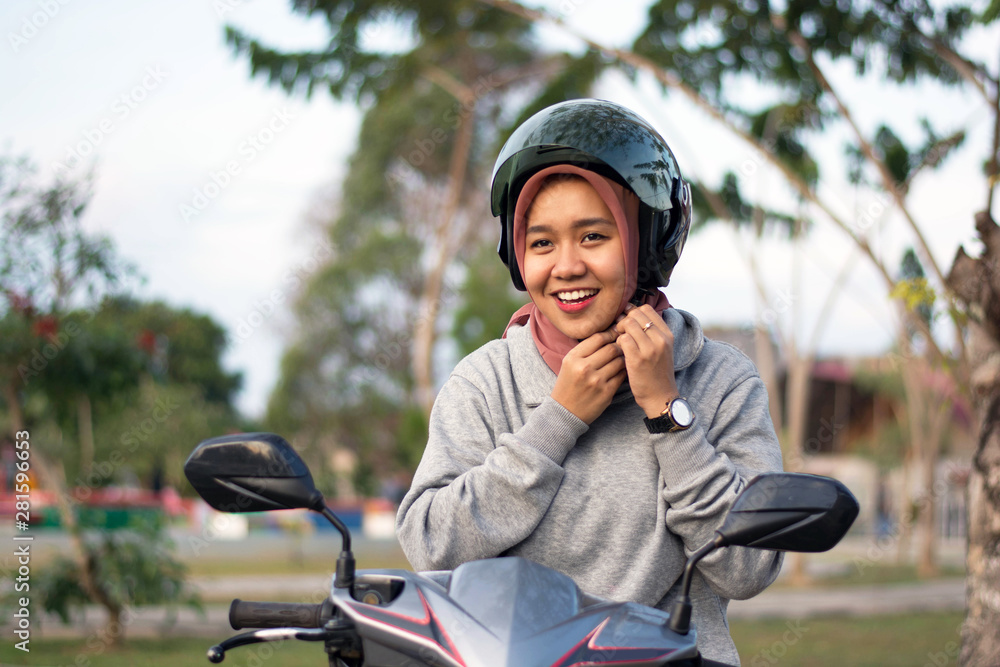 portrait of hijab woman wearing a helmet before riding a motorcycle in a park portrait of hijab woman wearing a helmet before riding a motorcycle in a park