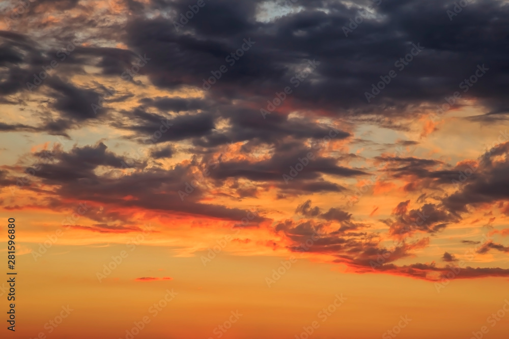 Heavenly summer background. Beautiful bright majestic dramatic evening sky at sunset or sunrise orange and blue with rays. The sun shines over the horizon against the backdrop of thunder clouds