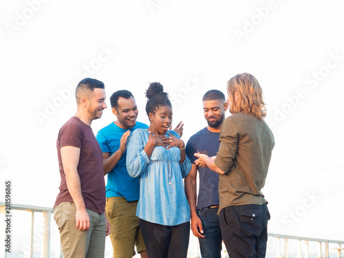 Smiling young people celebrating in summer park. Happy smiling friends standing in park with chocolate muffin. Concept of birthday celebration concept