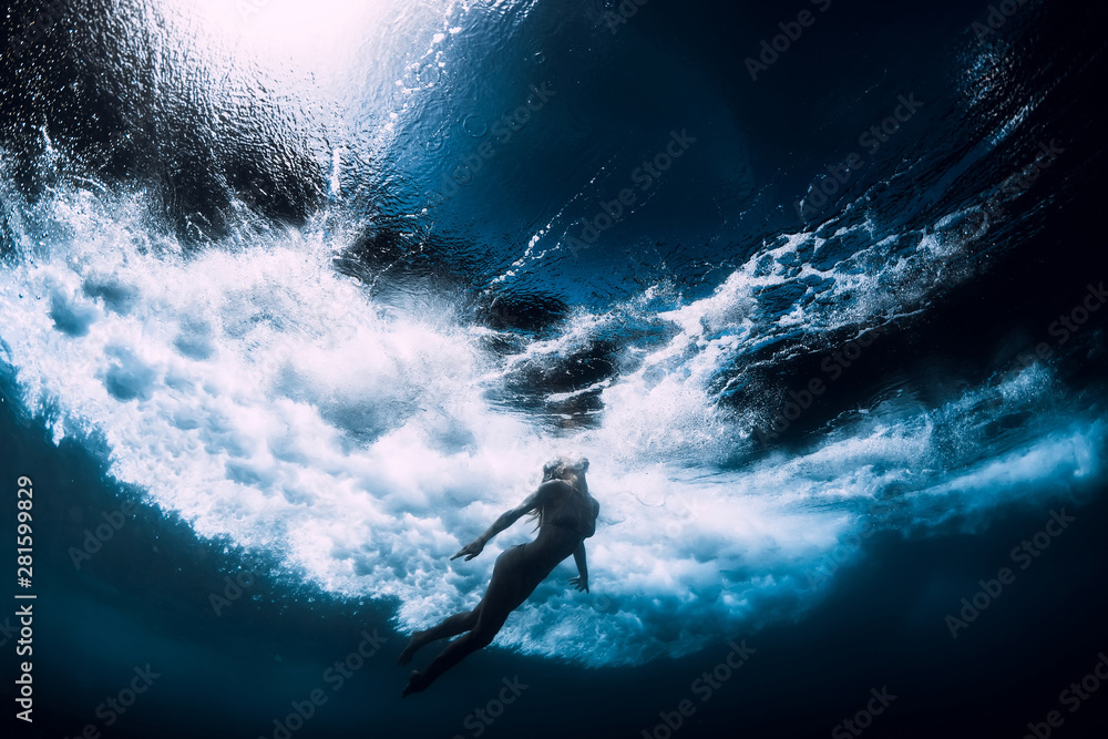 Fototapeta Kobieta nurkować pod wodą z dużą falą oceanu.