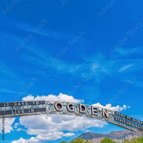 Square frame Welcome arch at the city of Ogden Utah against vivid blue sky and puffy clouds photo