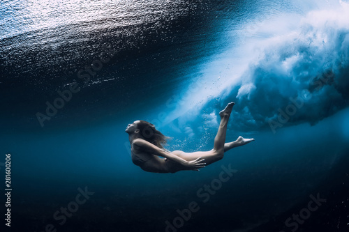 Woman swim underwater with ocean wave.