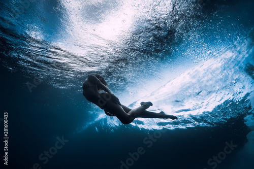 Woman dive underwater with ocean wave.