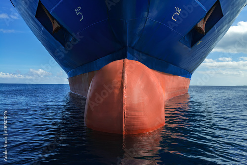 Close up of large blue merchant crago ship in the middle of the ocean underway. Performing cargo export and import operations.