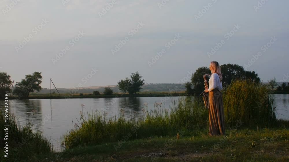 silhouette of a young woman playing on the saxophone near the riverbank at dawn, a beautiful girl in a long dress with a wind musical instrument in nature, a concept of hobby and relaxation silhouette of a young woman playing on the saxophone near the riverbank at dawn, a beautiful girl in a long dress with a wind musical instrument in nature, a concept of hobby and relaxation