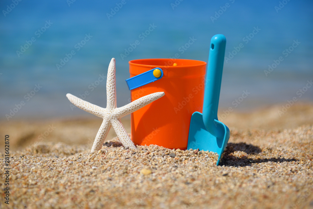 Bright plastic сhildren's beach toys and a starfish on sand near sea. Summer vacation concept Bright plastic сhildren's beach toys and a starfish on sand near sea. Summer vacation concept