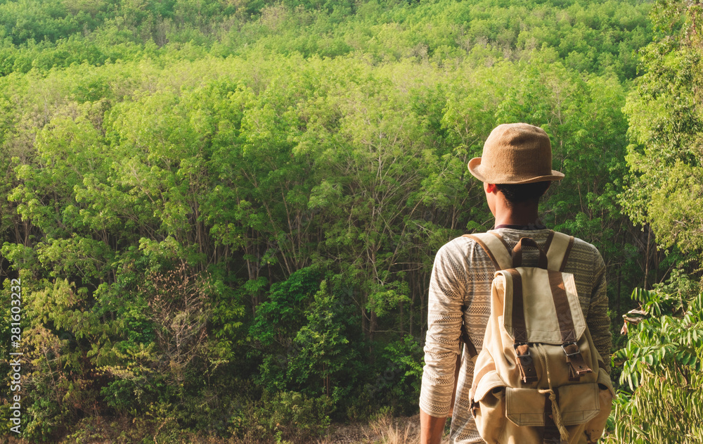 A man standing looking forest on mountains with backpack Travel Lifestyle wanderlust adventure concept summer vacations outdoor alone into the wild