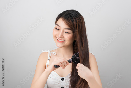 Hair care. Young Asian girl combing hair with finger isolated on white background