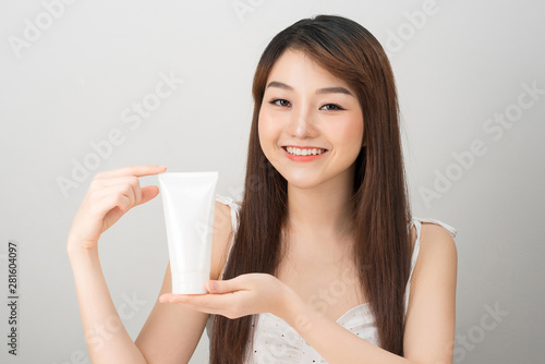 smiling young Asian woman showing skincare products
