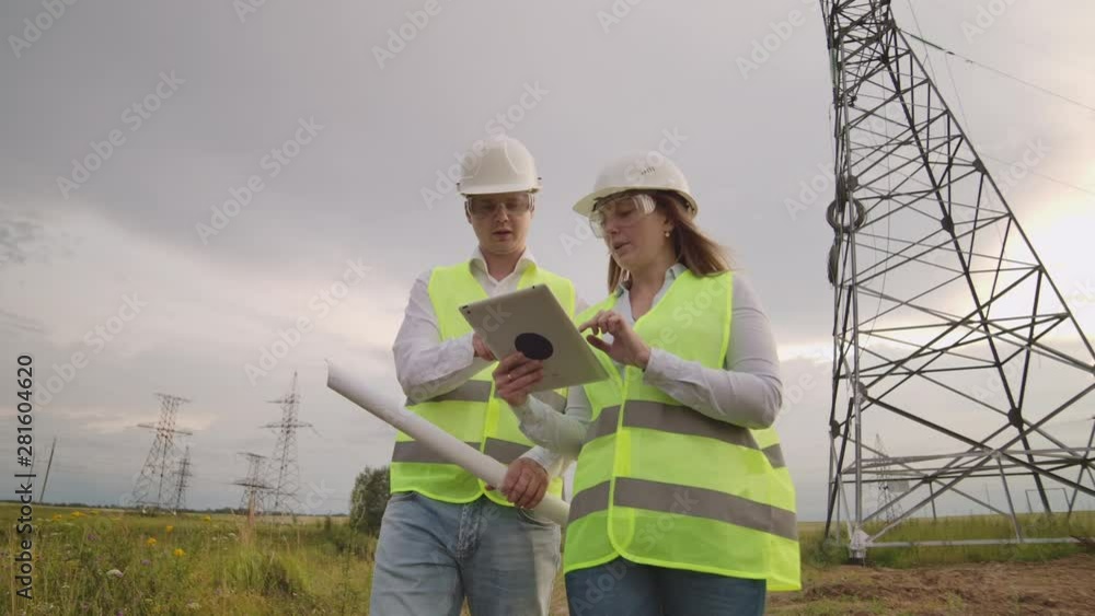 Engineer and supervisor with tablet PC and the drawings are about lines and transmission towers and discuss the expansion plan and transportation energy for towns and cities. Engineer and supervisor with tablet PC and the drawings are about lines and transmission towers and discuss the expansion plan and transportation energy for towns and cities.