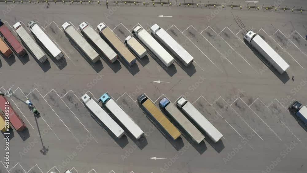 Aerial shot of car parking with trucks. Top view of semi-trailers in the open area with road markings. Aerial shot of car parking with trucks. Top view of semi-trailers in the open area with road markings.
