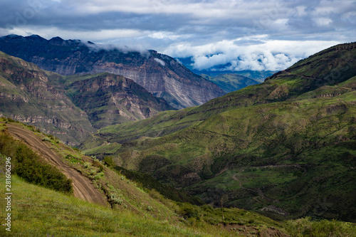 Mountain landscape beautiful green mountains with Alpine lush meadows cloudy sky background.