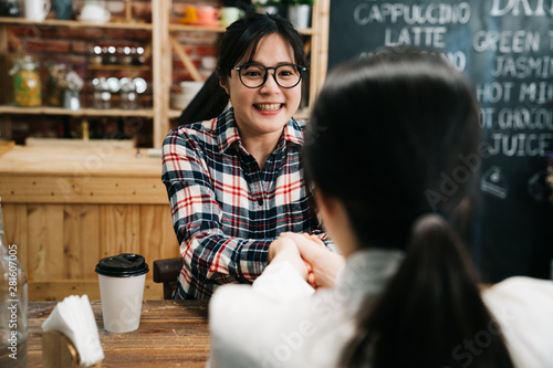 Fotografia Young asian woman in business employment interview shaking hands with personnel officer in coffee store