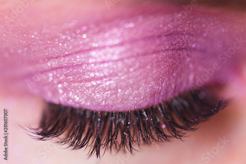 Beautiful false eyelashes and pink eyes shadow on closed eyelid closeup. Selective focus.
