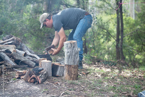 man chopping firewood for campfire