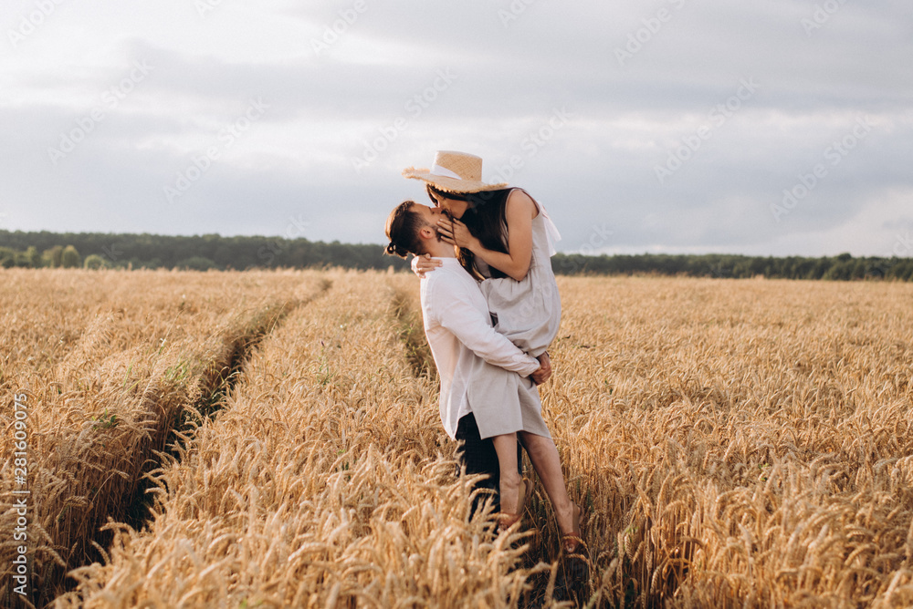 Outdoor shot of young couple walking through meadow hand in hand. Man and woman talking walk through Wheat Field in countryside. selective focus Outdoor shot of young couple walking through meadow hand in hand. Man and woman talking walk through Wheat Field in countryside. selective focus