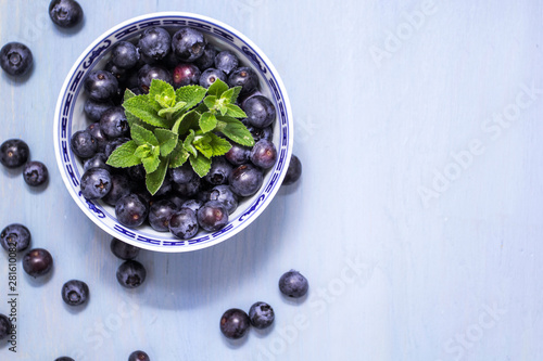 Blueberries in a bowl on wooden blue background
