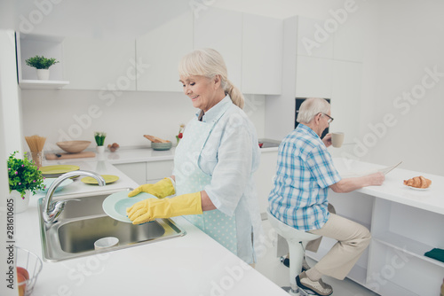 Portrait of nice cute old lady hold hand polishing drying plates wet hands enjoy house work have kitchenwear stand indoors
