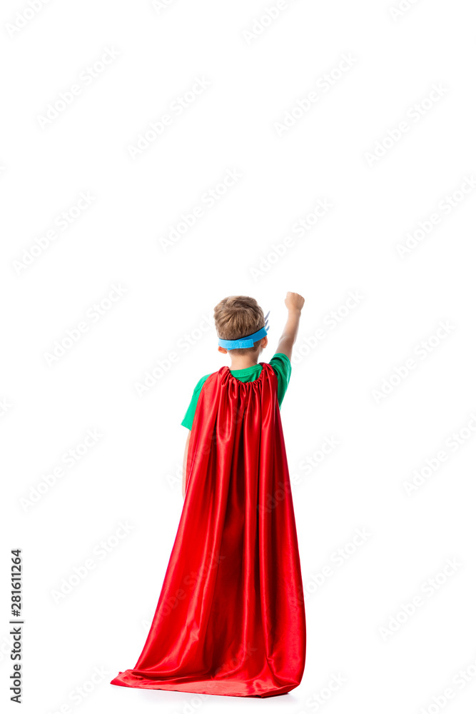back view of preschooler boy in red hero cloak standing with fist up isolated on white