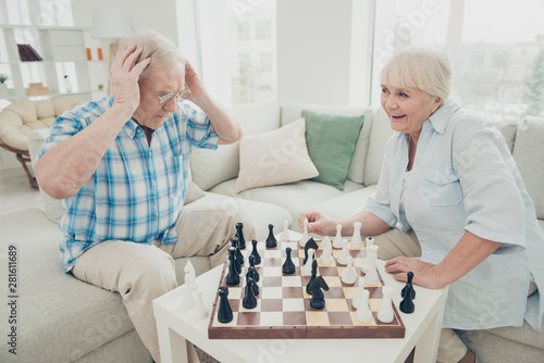 Portrait of his he her she two nice attractive cheerful cheery positive intelligent people creating move pieces win winner amateur championship in light white interior living-room house indoors