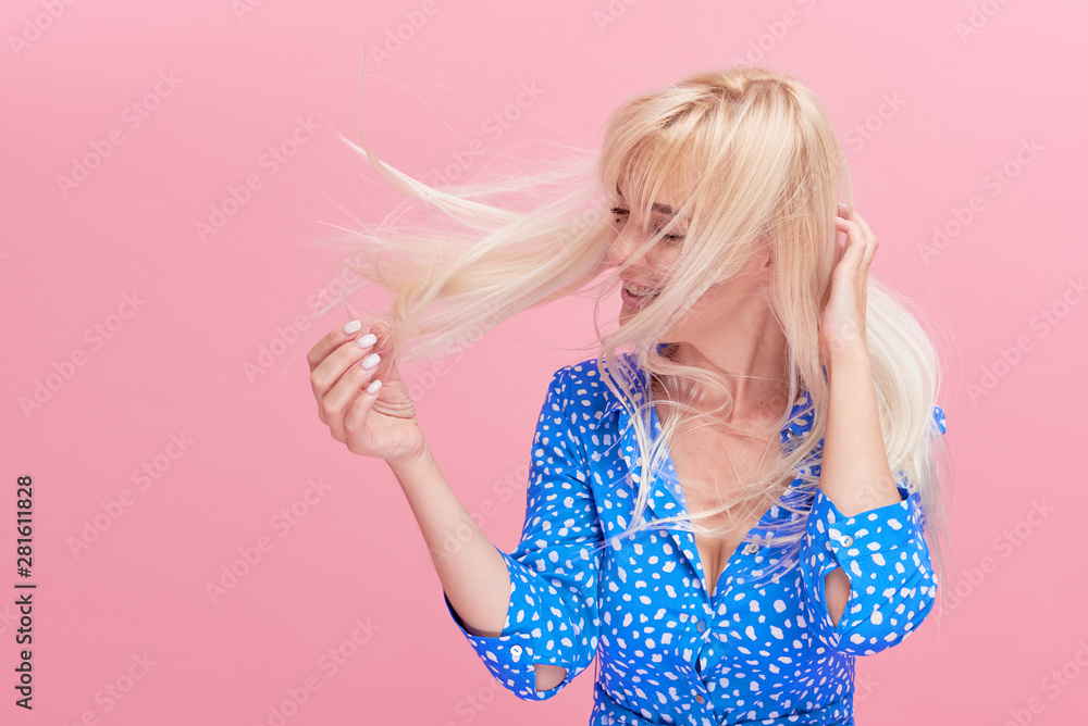Beauty Portrait of a beautiful young blond woman with amazing flowing hair. loose hair fluttering in the wind. Isolated on pink studio background. fresh air concept. Climate control