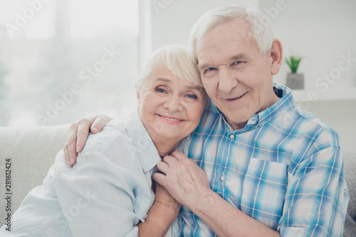 Close-up portrait of her she his he two nice attractive lovely kind sweet gentle cheerful cheery peaceful calm spouses hugging holding hands in light white interior room indoors