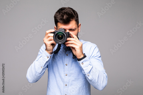 Young man take photo with dslr camera looking at camera isolated over gray abackground.