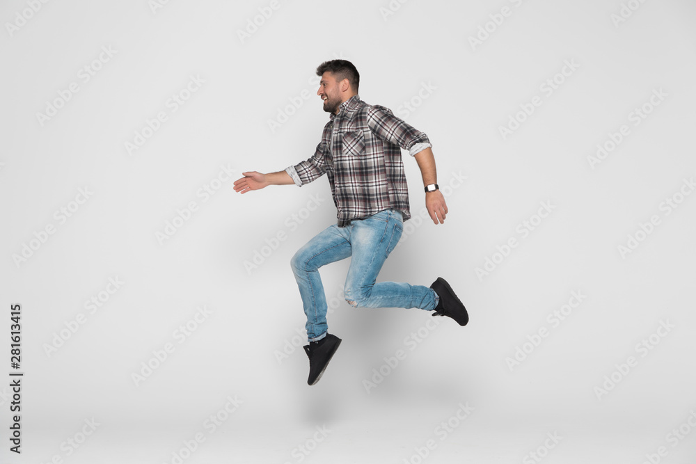 Happiness, freedom, movement and people concept. Smiling young man jumping in air isolated on white background