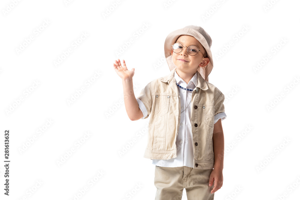 smiling explorer boy in hat and glasses looking at camera and waving hand isolated on white smiling explorer boy in hat and glasses looking at camera and waving hand isolated on white