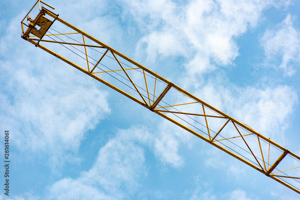 Part of a yellow construction crane against a blue sky