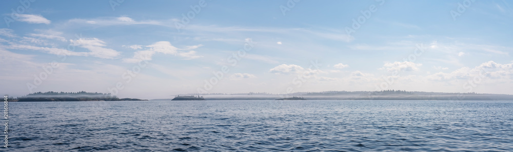 Evening landscape of the lake with waves, on the horizon a rocky shore with trees in the fog and the sky with clouds. Panorama. Russia. Karelia. Ladoga.