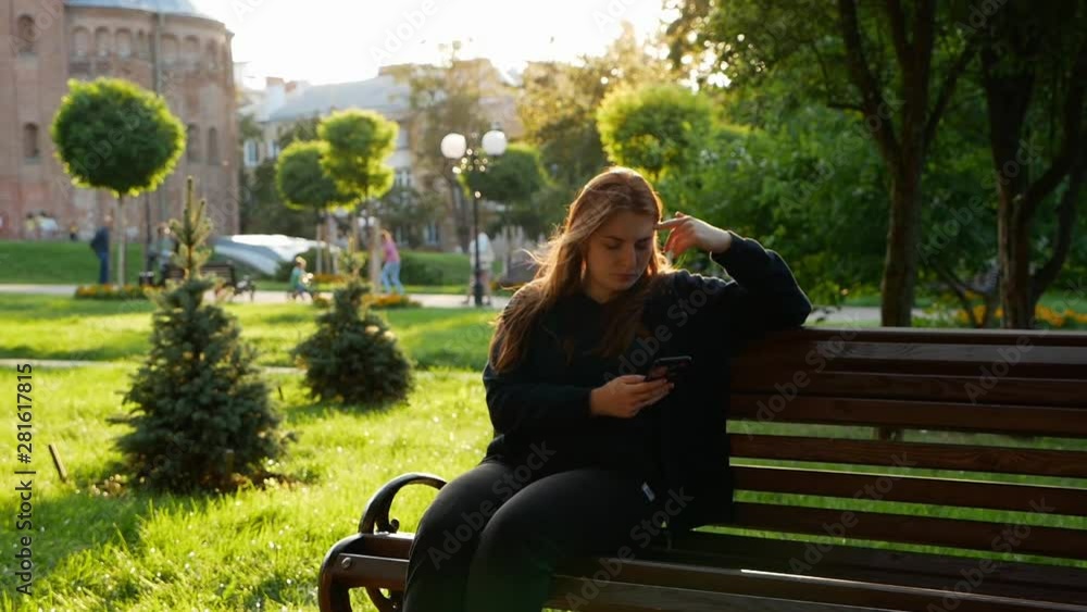 Red-haired girl sits on a bench in social networks Red-haired girl sits on a bench in social networks