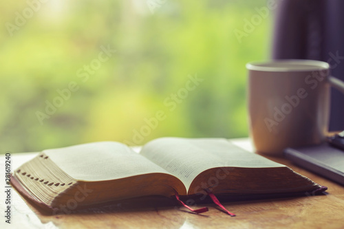 Canvas Print Open bible with a cup of coffee for morning devotion on wooden table with windo