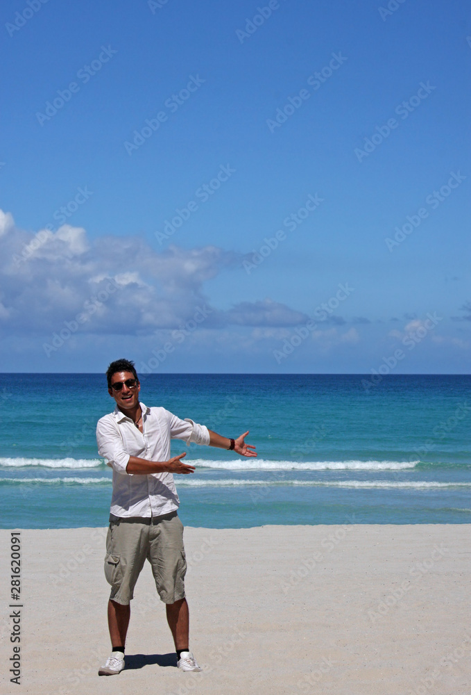 Young man with tan and sunglasses presenting something in the copy space area of the beach landscape. Young man with tan and sunglasses presenting something in the copy space area of the beach landscape.