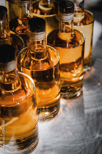 Small liquor production based on maple syrup. Multitude of pure alcohol bottles not labeled. Bottles placed in a row.