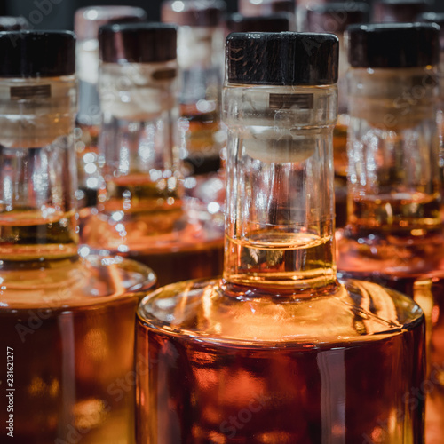 Small liquor production based on maple syrup. Multitude of pure alcohol bottles not labeled. Bottles placed in a row.