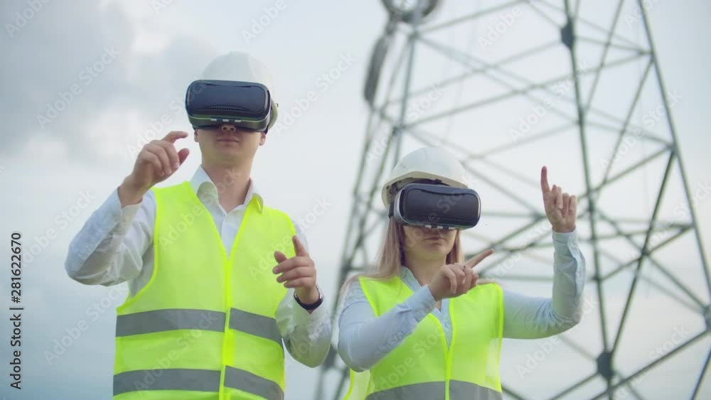 Two engineers of power engineers in VR glasses move their hands simulating the operation of the interface of the control system Two engineers of power engineers in VR glasses move their hands simulating the operation of the interface of the control system