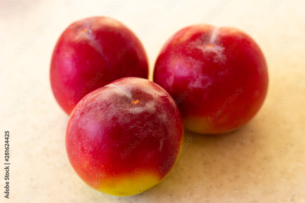 Fruit harvest. A lot of peaches, plums, apricots on the background of an old rural wooden surface. Red plum on white surface. Red plums