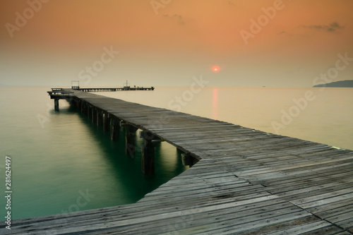  Wooden bridge that stretches into the sea at sunrise.