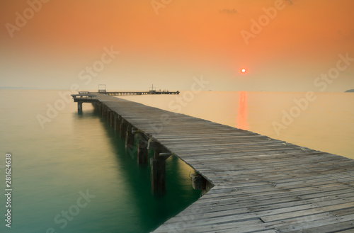  Wooden bridge that stretches into the sea at sunrise.